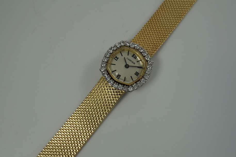 A very nice vintage Movado bracelet watch in 18k yellow gold, crafted during the late 1960s. Once retailed by Cartier, the subtle hexagonal polished case with original finish is surrounded by 28 diamonds weighing 1.12 carat total weight, houses a silver dial signed Cartier with black stick and Roman numerals and stick hands. Resembling a floral design further accentuated by a beautifully crafted integrated bracelet with a backwind function that adds to its daintiness. Suitable for casual and dressy occasions.