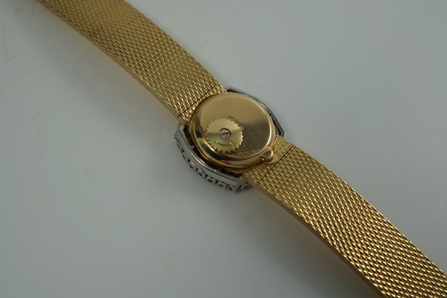 A very nice vintage Movado bracelet watch in 18k yellow gold, crafted during the late 1960s. Once retailed by Cartier, the subtle hexagonal polished case with original finish is surrounded by 28 diamonds weighing 1.12 carat total weight, houses a silver dial signed Cartier with black stick and Roman numerals and stick hands. Resembling a floral design further accentuated by a beautifully crafted integrated bracelet with a backwind function that adds to its daintiness. Suitable for casual and dressy occasions.