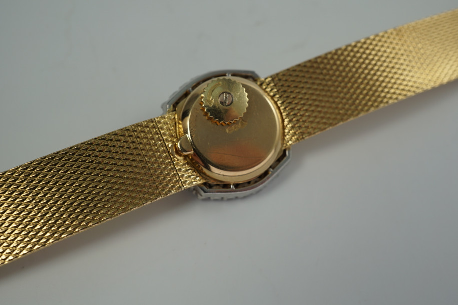 A very nice vintage Movado bracelet watch in 18k yellow gold, crafted during the late 1960s. Once retailed by Cartier, the subtle hexagonal polished case with original finish is surrounded by 28 diamonds weighing 1.12 carat total weight, houses a silver dial signed Cartier with black stick and Roman numerals and stick hands. Resembling a floral design further accentuated by a beautifully crafted integrated bracelet with a backwind function that adds to its daintiness. Suitable for casual and dressy occasions.