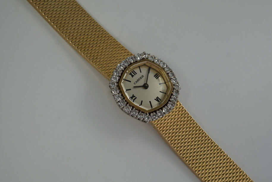 A very nice vintage Movado bracelet watch in 18k yellow gold, crafted during the late 1960s. Once retailed by Cartier, the subtle hexagonal polished case with original finish is surrounded by 28 diamonds weighing 1.12 carat total weight, houses a silver dial signed Cartier with black stick and Roman numerals and stick hands. Resembling a floral design further accentuated by a beautifully crafted integrated bracelet with a backwind function that adds to its daintiness. Suitable for casual and dressy occasions.