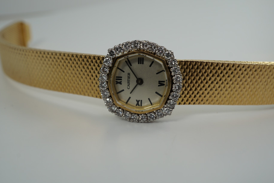 A very nice vintage Movado bracelet watch in 18k yellow gold, crafted during the late 1960s. Once retailed by Cartier, the subtle hexagonal polished case with original finish is surrounded by 28 diamonds weighing 1.12 carat total weight, houses a silver dial signed Cartier with black stick and Roman numerals and stick hands. Resembling a floral design further accentuated by a beautifully crafted integrated bracelet with a backwind function that adds to its daintiness. Suitable for casual and dressy occasions.