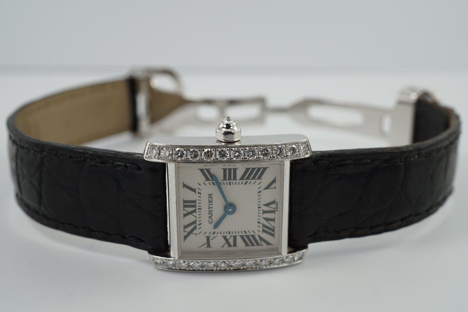 BRAND:                            Cartier
MODEL:                            Tank Française 
CASE MATERIAL:            18k white gold
CASE MEASURES:          20 x 25 mm
MOVEMENT:                     Quartz
FUNCTIONS:                    Time 
CONDITION:                     Excellent
See it in our eBay store.
A fine preowned Cartier Tank Française, crafted during the 2000s. A dainty accessory with beautifully set diamonds elevating its presence on the wrist. Classic Roman numeral white dial paired with a black alligator strap that would suit a variety of settings and wardrobes. Modeled on size 6 inch wrist. 

Original dial, hands and crown.
Case measures 20 x 25 mm, 6mm thick.
Cartier quartz movement.
Serial# MG283899
Sapphire crystal.
Cartier black alligator strap (80% condition).
Cartier 18k deployment buckle. 
15 mm lug width.