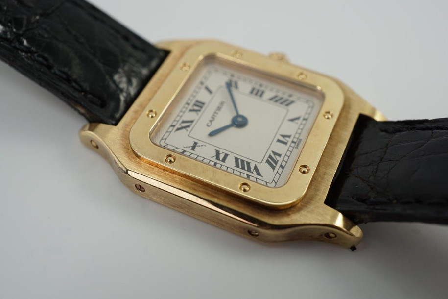 BRAND:                            Cartier 
MODEL:                            Santos Dumont  
CASE MATERIAL:            18k Yellow Gold
CASE MEASURES:          23 x 32 mm
MOVEMENT:                     Mechanical
FUNCTIONS:                    Time
CONDITION:                     Very good
See it in our eBay store.
A beautiful Cartier Santos Dumont Extra Plate in 18k yellow gold, crafted during the 1990s. This model is in a size that is a nice in-between, wearing minimally on the wrist with its thin profile, catching the light at times with the polished finish of the bezel. The contrasting polishes of the case and bezel almost gives it a two-tone effect, further accentuated with the beautiful guilloche dial. Modeled on size 6 inch wrist. 

Light scratches and nicks.
Original dial, hands and crown.
Case measures 23 x 32 mm, 4mm thick.
Cartier cal. 21, 17 jewels mechanical winding.
Serial# 8210530xxx
Sapphire crystal.
Cartier black alligator strap (85% condition).
Cartier 18k gold buckle. 
13 mm lug width.