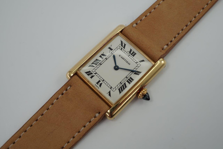 BRAND:                            Cartier 
MODEL:                            Tank
CASE MATERIAL:            18k yellow gold 
CASE MEASURES:          24 x 30 mm
MOVEMENT:                     Mechanical winding
FUNCTIONS:                    Time 
CONDITION:                     Very good
See it in our eBay store.
A beautiful vintage Cartier Tank L.C. in 18k yellow gold, crafted during the 1980s. A special and more refined version of the Tanks, with the extra flat profile, elongated sapphire crown and Paris dial. Would suit a varied wardrobe for an elegant or casual look. Modeled on size 6 inch wrist. 

Tarnishing on case, slight scratches.
Original white Roman dial signed PARIS.
Original blued hands and elongated sapphire crown. 
Case measures 24 x 30 mm, 5 mm thick. 
Cartier cal. 8061 (96), 18 jewels mechanical winding, adjusted to 5 positions. 
Original Cartier 18k deployment with black Must Cartier lizard strap, circumference measures
We will include a non-Cartier leather strap with non-Cartier buckle.
18 mm between lugs.