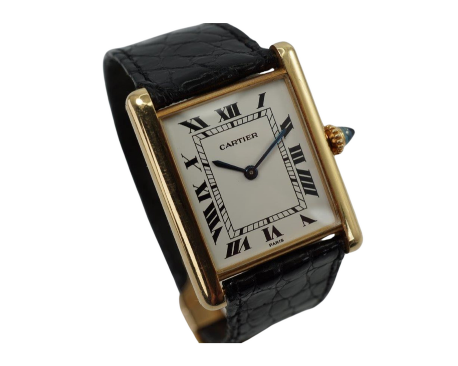 BRAND:                            Cartier 
MODEL:                            Tank
CASE MATERIAL:            18k yellow gold 
CASE MEASURES:          24 x 30 mm
MOVEMENT:                     Mechanical winding
FUNCTIONS:                    Time 
CONDITION:                     Very good
See it in our eBay store.
A beautiful vintage Cartier Tank L.C. in 18k yellow gold, crafted during the 1980s. A special and more refined version of the Tanks, with the extra flat profile, elongated sapphire crown and Paris dial. Would suit a varied wardrobe for an elegant or casual look. Modeled on size 6 inch wrist. 

Tarnishing on case, slight scratches.
Original white Roman dial signed PARIS.
Original blued hands and elongated sapphire crown. 
Case measures 24 x 30 mm, 5 mm thick. 
Cartier cal. 8061 (96), 18 jewels mechanical winding, adjusted to 5 positions. 
Original Cartier 18k deployment with black Must Cartier lizard strap, circumference measures
We will include a non-Cartier leather strap with non-Cartier buckle.
18 mm between lugs.