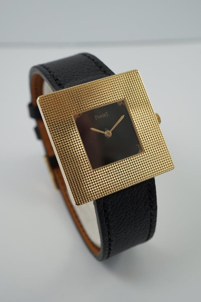 BRAND:                           Piaget
MODEL:                           Square
CASE MATERIAL:            18k yellow gold
CASE MEASURES:          28 mm
MOVEMENT:                     Mechanical winding
FUNCTIONS:                    Time
CONDITION:                     Fine
See it in our eBay store.

A fine rare vintage Piaget square reference 99014 in 18k yellow gold, crafted during the 1970s. At first glance, a minimal piece with its thin profile and black and gold configuration. More meets the eye, however, with the attractive hobnail bezel that softens the bold square frame, and harmoniously symmetrical in scale to the face. Suitable for casual and dressy occasions. Modeled on a 6 inch wrist. 

Light scratches, dial’s corners show underlying gold finish. 
Original black dial, hands and crown. 
Square face measures 14 mm.
Case measures 28 mm, 4.3 mm thick. 
Piaget cal. 9PZ, 18 jewels mechanical winding.
Serial# 2754xx Movement# 768476
Sapphire crystal.
Premium new non-Piaget black leather strap.
Piaget 18k gold buckle.
17 mm between lugs.