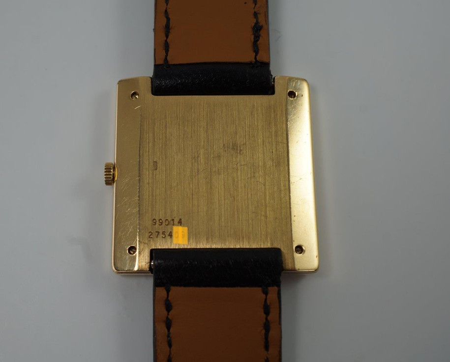 BRAND:                           Piaget
MODEL:                           Square
CASE MATERIAL:            18k yellow gold
CASE MEASURES:          28 mm
MOVEMENT:                     Mechanical winding
FUNCTIONS:                    Time
CONDITION:                     Fine
See it in our eBay store.

A fine rare vintage Piaget square reference 99014 in 18k yellow gold, crafted during the 1970s. At first glance, a minimal piece with its thin profile and black and gold configuration. More meets the eye, however, with the attractive hobnail bezel that softens the bold square frame, and harmoniously symmetrical in scale to the face. Suitable for casual and dressy occasions. Modeled on a 6 inch wrist. 

Light scratches, dial’s corners show underlying gold finish. 
Original black dial, hands and crown. 
Square face measures 14 mm.
Case measures 28 mm, 4.3 mm thick. 
Piaget cal. 9PZ, 18 jewels mechanical winding.
Serial# 2754xx Movement# 768476
Sapphire crystal.
Premium new non-Piaget black leather strap.
Piaget 18k gold buckle.
17 mm between lugs.