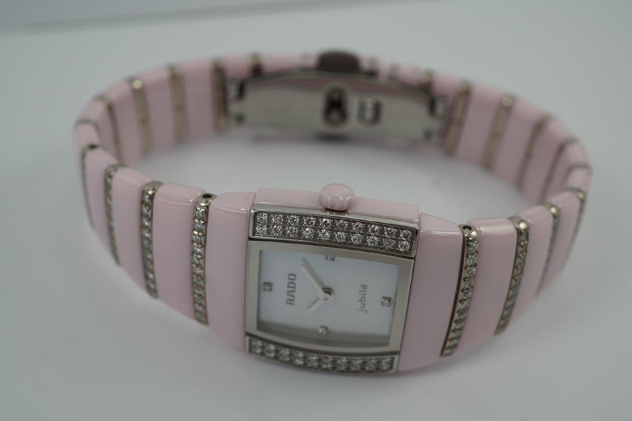 BRAND:                          Rado
MODEL:                          Sintra Jubile 
CASE MATERIAL:           Ceramic and diamond
CASE MEASURES:          22 x 27 mm
MOVEMENT:                   Quartz  
FUNCTIONS:                   Time
CONDITION:                    Fine
See it in our eBay store.

A very nice preowned Rado Sintra Jubilee in ceramic, crafted during the 2010s. A sweet little watch for the wearer who enjoys wearing a delicate pink watch with accented diamond bezel and bracelet, featuring a mother of pearl dial and diamond hour markers. Wears comfortably with its size and weight, and double-fold clasp. The crown is in the shape of a flower that makes this piece extra special. Modeled on size 6 inch wrist.

Minimal scratches. 
Factory diamond bezel, mop diamond dial and 8 rows of graduating diamonds. 
Case measures 22 x 27 mm, 7.5mm thick.
Rado quartz movement.
Serial# 1D118056
Sapphire crystal.
Rado bracelet fits 6 1/2 inches.
18mm graduated bracelet.
Last known retail: 5,600 USD.