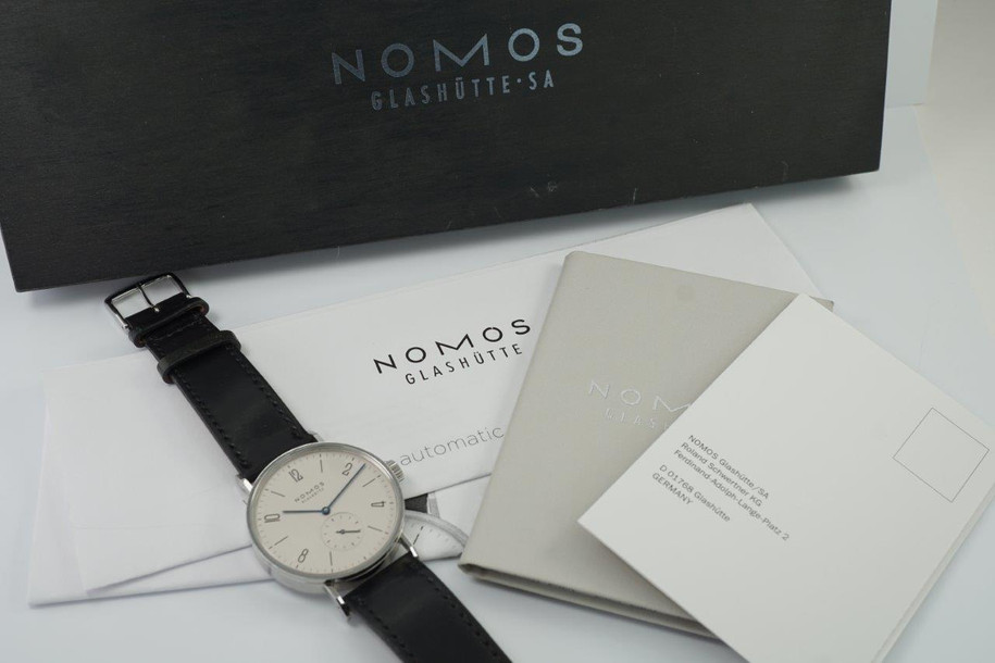 A fine preowned NOMOS Glashutte Tangomat in stainless steel, crafted circa 2008-10. A minimal and sturdy accessory of famed German craftmanship, featuring tonal silver dial with subsidiary dial, blue hands and black markers. The 38mm size circumvents overpowering the wrist while preserving a statement with its slightly bold profile and angular grasshopper-style lugs, with a glass exhibition to the beautiful movement. Modeled on 6 inch wrist.

Minimal wear.
Box and papers included.
Case measures 38 x 48 mm, 8.5 thick.
NOMOS cal., 26 jewel automatic winding. 
Serial# 2645
Sapphire crystal.
NOMOS black Shell Cordovan strap (75-80% condition approximate).
NOMOS steel buckle. 
USD retail approx. 3280 USD
20mm between lugs.