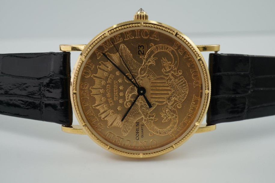 A fine Corum 20 Dollar Coin watch in 18k yellow gold, crafted during the 1990s. USA coin from 1897 exhibits little wear, with the classic ridged coin case and diamond crown. Durable for everyday wear, features a date aperture and black hands contrasting delightfully against the gold face, paired with a glossy alligator black strap. Modeled on 6 inch wrist.

Box included.
Original dial, hands and crown. 
Case measures 36 x 42 mm, 6 mm thick. 
Corum quartz, 10 jewels 
Case# 3763xx Movement# 2194xx
Sapphire crystal. 
Corum black alligator strap, unused.
Corum plated buckle. 
20mm lug width.