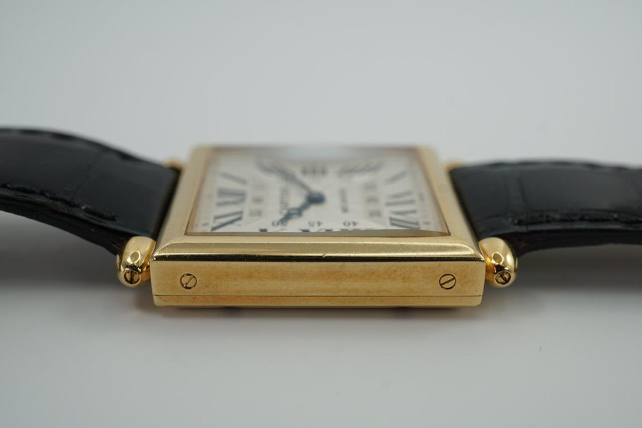 A fine preowned Cartier Tank Obus 2380 in 18k yellow gold, crafted circa 1998. The Obus is an iteration of the century-old Tank from Cartier, the name deriving from the French word “bullet” referencing the bullet-shaped lugs. The case sits prominently on the wrist without overwhelming the wearer, encompassing the silver guilloche dial, blued breguet hands black Roman numerals and blue sapphire cabochon crown. From the Collection Privée Cartier Paris line, the exhibition case back reveals the Cartier movement with special attention to interlocking C logo design making this an excellent piece for the collector’s repertoire. Modeled on 6 inch wrist.

Light tarnish.
Includes CPCP inner and outer box, and papers.
Original guilloche dial, blued breguet hands and Cartier crown. 
Case measures 26.5 x 33.5 mm, 8 mm thick. 
Cartier cal. 1585MC, 18 jewel mechanical.
Serial# CC451xxx Movement# 0843
Sapphire crystal. 
Cartier black crocodile strap (85% condition).
Cartier 18k yellow gold buckle. 
17 mm lug width.