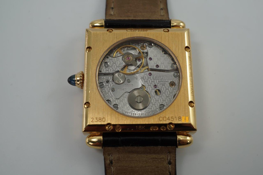 A fine preowned Cartier Tank Obus 2380 in 18k yellow gold, crafted circa 1998. The Obus is an iteration of the century-old Tank from Cartier, the name deriving from the French word “bullet” referencing the bullet-shaped lugs. The case sits prominently on the wrist without overwhelming the wearer, encompassing the silver guilloche dial, blued breguet hands black Roman numerals and blue sapphire cabochon crown. From the Collection Privée Cartier Paris line, the exhibition case back reveals the Cartier movement with special attention to interlocking C logo design making this an excellent piece for the collector’s repertoire. Modeled on 6 inch wrist.

Light tarnish.
Includes CPCP inner and outer box, and papers.
Original guilloche dial, blued breguet hands and Cartier crown. 
Case measures 26.5 x 33.5 mm, 8 mm thick. 
Cartier cal. 1585MC, 18 jewel mechanical.
Serial# CC451xxx Movement# 0843
Sapphire crystal. 
Cartier black crocodile strap (85% condition).
Cartier 18k yellow gold buckle. 
17 mm lug width.