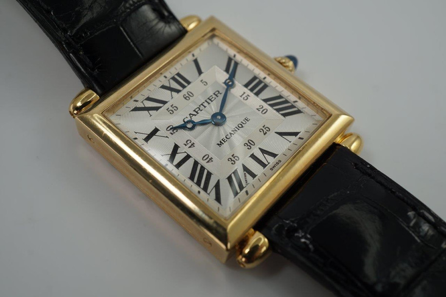 A fine preowned Cartier Tank Obus 2380 in 18k yellow gold, crafted circa 1998. The Obus is an iteration of the century-old Tank from Cartier, the name deriving from the French word “bullet” referencing the bullet-shaped lugs. The case sits prominently on the wrist without overwhelming the wearer, encompassing the silver guilloche dial, blued breguet hands black Roman numerals and blue sapphire cabochon crown. From the Collection Privée Cartier Paris line, the exhibition case back reveals the Cartier movement with special attention to interlocking C logo design making this an excellent piece for the collector’s repertoire. Modeled on 6 inch wrist.

Light tarnish.
Includes CPCP inner and outer box, and papers.
Original guilloche dial, blued breguet hands and Cartier crown. 
Case measures 26.5 x 33.5 mm, 8 mm thick. 
Cartier cal. 1585MC, 18 jewel mechanical.
Serial# CC451xxx Movement# 0843
Sapphire crystal. 
Cartier black crocodile strap (85% condition).
Cartier 18k yellow gold buckle. 
17 mm lug width.