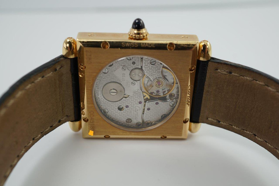 A fine preowned Cartier Tank Obus 2380 in 18k yellow gold, crafted circa 1998. The Obus is an iteration of the century-old Tank from Cartier, the name deriving from the French word “bullet” referencing the bullet-shaped lugs. The case sits prominently on the wrist without overwhelming the wearer, encompassing the silver guilloche dial, blued breguet hands black Roman numerals and blue sapphire cabochon crown. From the Collection Privée Cartier Paris line, the exhibition case back reveals the Cartier movement with special attention to interlocking C logo design making this an excellent piece for the collector’s repertoire. Modeled on 6 inch wrist.