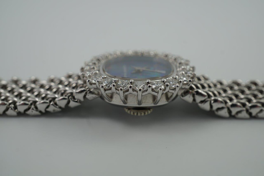 A fine vintage Audemars Piguet opal and diamond bracelet watch in 18k white gold, crafted during the 1980s. A stunning oval accessory for the fiery gem quality opal dial Audemars is renowned in selecting for their fine pieces, surrounded by round brilliant cut diamonds. Both the opal and diamonds catch the light in a way that refracts a glitter of rainbow colors. This piece will dazzle the wearer and suit a variety of occasions, its interlinked chain bracelet wearing comfortably on the wrist. Modeled on 6 inch wrist.

The opal has faint crack at 4 o’clock position that is imperceptible with the naked eye due to the competing opal. Light scratch on center crystal. 
Factory round cut .10 carat diamond set bezel; 2 carats total approximate.
Original opal dial, hands and crown. 
Case measures 21.5 x 22.5 mm, 6.5 mm thick. 
AP cal. 2430, 18 jewel backwind set movement. 
Case# 194xx Movement# 2636xx
Sapphire crystal. 
AP signed bracelet, measures and fits 6 3/4 inches or 17cm approximate, 12mm wide.