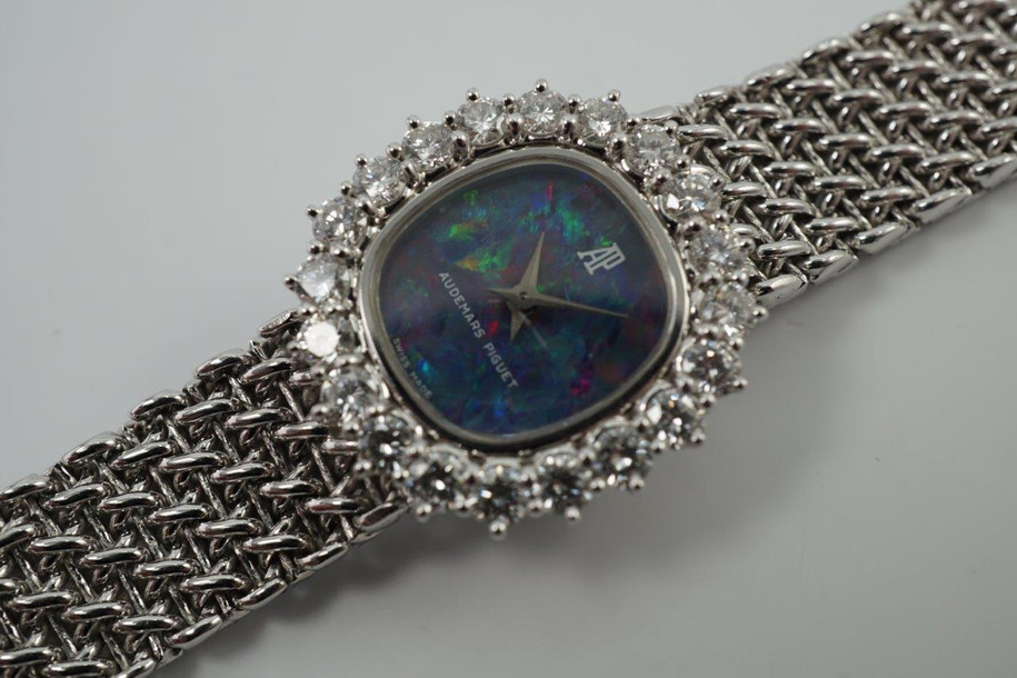 A fine vintage Audemars Piguet opal and diamond bracelet watch in 18k white gold, crafted during the 1980s. A stunning oval accessory for the fiery gem quality opal dial Audemars is renowned in selecting for their fine pieces, surrounded by round brilliant cut diamonds. Both the opal and diamonds catch the light in a way that refracts a glitter of rainbow colors. This piece will dazzle the wearer and suit a variety of occasions, its interlinked chain bracelet wearing comfortably on the wrist. Modeled on 6 inch wrist.

The opal has faint crack at 4 o’clock position that is imperceptible with the naked eye due to the competing opal. Light scratch on center crystal. 
Factory round cut .10 carat diamond set bezel; 2 carats total approximate.
Original opal dial, hands and crown. 
Case measures 21.5 x 22.5 mm, 6.5 mm thick. 
AP cal. 2430, 18 jewel backwind set movement. 
Case# 194xx Movement# 2636xx
Sapphire crystal. 
AP signed bracelet, measures and fits 6 3/4 inches or 17cm approximate, 12mm wide.