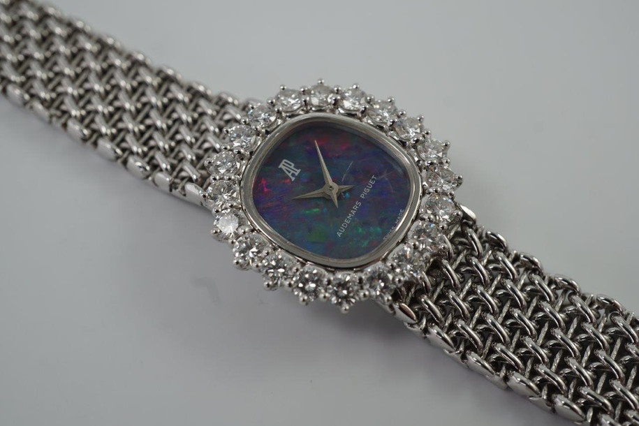 A fine vintage Audemars Piguet opal and diamond bracelet watch in 18k white gold, crafted during the 1980s. A stunning oval accessory for the fiery gem quality opal dial Audemars is renowned in selecting for their fine pieces, surrounded by round brilliant cut diamonds. Both the opal and diamonds catch the light in a way that refracts a glitter of rainbow colors. This piece will dazzle the wearer and suit a variety of occasions, its interlinked chain bracelet wearing comfortably on the wrist. Modeled on 6 inch wrist.

The opal has faint crack at 4 o’clock position that is imperceptible with the naked eye due to the competing opal. Light scratch on center crystal. 
Factory round cut .10 carat diamond set bezel; 2 carats total approximate.
Original opal dial, hands and crown. 
Case measures 21.5 x 22.5 mm, 6.5 mm thick. 
AP cal. 2430, 18 jewel backwind set movement. 
Case# 194xx Movement# 2636xx
Sapphire crystal. 
AP signed bracelet, measures and fits 6 3/4 inches or 17cm approximate, 12mm wide.