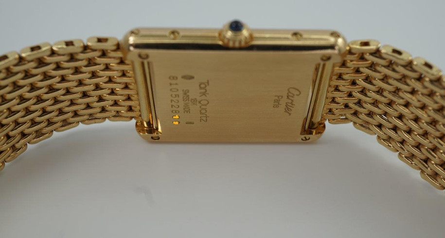 A fine preowned Cartier Tank Grains of Rice in 18k yellow gold, crafted during the 1990s. A special edition of the popular and enduring Tank model for its bracelet charmingly described as grain or beads of rice. The classic white Roman dial with blued steel hands paired with the bracelet serves a dressy look, alternatively a leather strap will tone it down  for more casual feel. Wonderfully drapes the wrist and is comfortable to wear, suitable for men or woman. Modeled on 6 inch wrist.

Light scratches and small nick on crystal. 
Original dial, hands and sapphire crown. 
Case measures 23.5 x 31 mm, 6 mm thick. 
Sapphire crystal. 
Cartier quartz movement. 
Serial# 810522xxx
Cartier bracelet has been previously fitted. Fits 6 1/2 inch or 17 cm approximate.
New non-Cartier black leather strap.
17.5 wide.