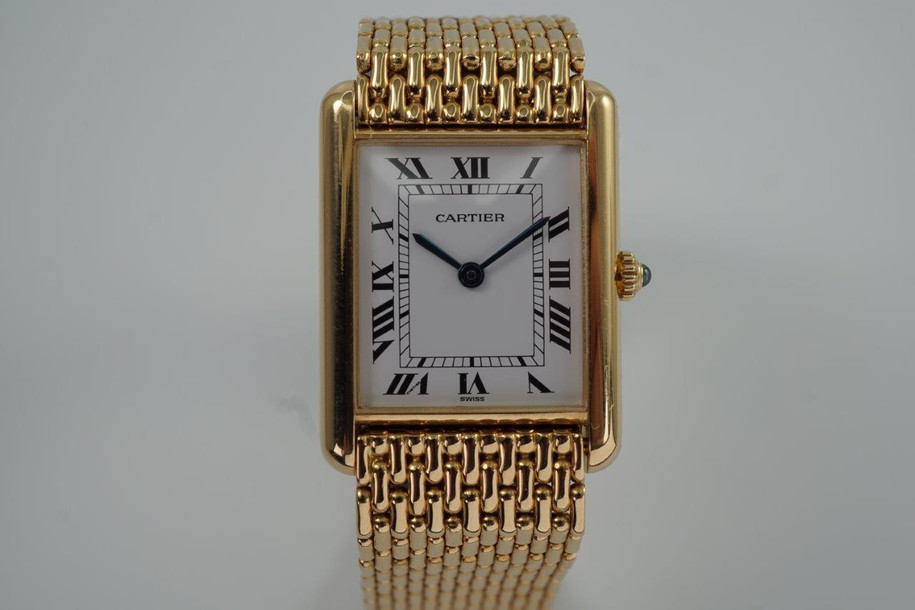 A fine preowned Cartier Tank Grains of Rice in 18k yellow gold, crafted during the 1990s. A special edition of the popular and enduring Tank model for its bracelet charmingly described as grain or beads of rice. The classic white Roman dial with blued steel hands paired with the bracelet serves a dressy look, alternatively a leather strap will tone it down  for more casual feel. Wonderfully drapes the wrist and is comfortable to wear, suitable for men or woman. Modeled on 6 inch wrist.

Light scratches and small nick on crystal. 
Original dial, hands and sapphire crown. 
Case measures 23.5 x 31 mm, 6 mm thick. 
Sapphire crystal. 
Cartier quartz movement. 
Serial# 810522xxx
Cartier bracelet has been previously fitted. Fits 6 1/2 inch or 17 cm approximate.
New non-Cartier black leather strap.
17.5 wide.