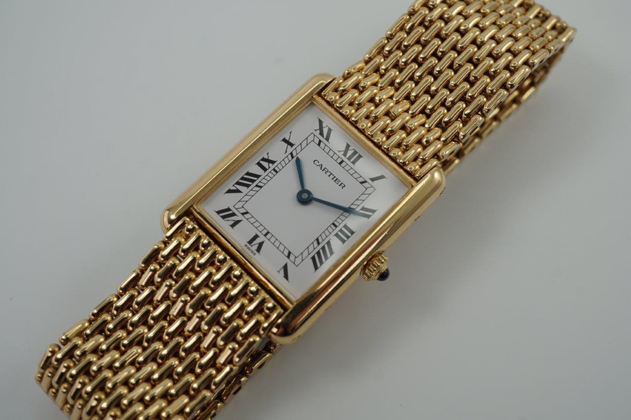 A fine preowned Cartier Tank Grains of Rice in 18k yellow gold, crafted during the 1990s. A special edition of the popular and enduring Tank model for its bracelet charmingly described as grain or beads of rice. The classic white Roman dial with blued steel hands paired with the bracelet serves a dressy look, alternatively a leather strap will tone it down  for more casual feel. Wonderfully drapes the wrist and is comfortable to wear, suitable for men or woman. Modeled on 6 inch wrist.

Light scratches and small nick on crystal. 
Original dial, hands and sapphire crown. 
Case measures 23.5 x 31 mm, 6 mm thick. 
Sapphire crystal. 
Cartier quartz movement. 
Serial# 810522xxx
Cartier bracelet has been previously fitted. Fits 6 1/2 inch or 17 cm approximate.
New non-Cartier black leather strap.
17.5 wide.