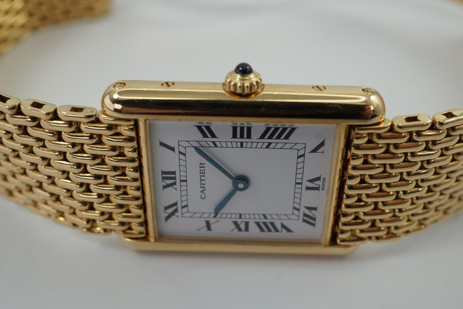 A fine preowned Cartier Tank Grains of Rice in 18k yellow gold, crafted during the 1990s. A special edition of the popular and enduring Tank model for its bracelet charmingly described as grain or beads of rice. The classic white Roman dial with blued steel hands paired with the bracelet serves a dressy look, alternatively a leather strap will tone it down  for more casual feel. Wonderfully drapes the wrist and is comfortable to wear, suitable for men or woman. Modeled on 6 inch wrist.

Light scratches and small nick on crystal. 
Original dial, hands and sapphire crown. 
Case measures 23.5 x 31 mm, 6 mm thick. 
Sapphire crystal. 
Cartier quartz movement. 
Serial# 810522xxx
Cartier bracelet has been previously fitted. Fits 6 1/2 inch or 17 cm approximate.
New non-Cartier black leather strap.
17.5 wide.