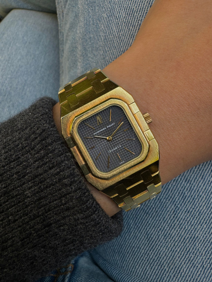 A very nice vintage Audemars Piguet Royal Oak in 18k yellow gold, crafted from the mid to late 1980s. The gold hours, hands and AP hallmark vividly stand out against the dark grey tapisserie dial in the light, complementing the boldness of the square rectangular case and bracelet. A lovely everyday piece that wears comfortably on the wrist with a thin profile and closure. 

Original finish shows normal wear due to use. 
Original tapisserie dial, gold hands and gold crown. 
Case measures 25 x 33 mm. 
AP cal. 2502, 7 Jewel quartz movement.
Serial# B604xx Movement# 213740 
Sapphire crystal. 
Original Audemars bracelet fits 6 1/8 inch or 15.5cm approximate.
18mm lug width. 
Modeled on 6 inch wrist.