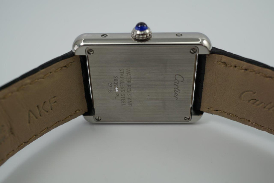 A fine preowned Cartier Tank Solo reference 2716 in stainless steel, crafted circa 2015. A casual everyday accessory, with the 6mm profile case encasing a white Roman dial, black Roman numeral hours with hidden Cartier hallmark at 10 o’clock, and blued steel hands. Paired with a black crocodile strap and blue sapphire cabochon crown, this classic configuration of the popular Tank will serve a variety of occasions. 

Minimal scratches. 
Original dial, hands and crown
Case measures 24 x 31 mm, 6mm thick. 
Cartier quartz movement. 
Sapphire crystal. 
Cartier adjustable black crocodile strap (90% condition), fits 6 3/4 inches.
Cartier steel deployment. 
17mm lug width. 
Modeled on 6 inch wrist.