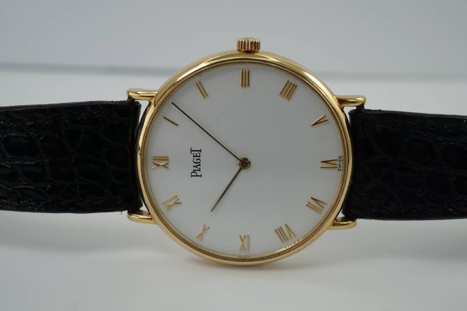 A very nice preowned Piaget watch in 18k yellow gold reference 8035, crafted during the 1990-2000s. A classic configuration of understated gold round smooth case, white dial and gold applied hours and Roman numerals. This piece will take you from executive look to a casual occasion, featuring an ultra-thin profile and paired with a black strap. Suitable for men or women.

Minimal scratches. 
Original dial, hands and crown.
Case measures 32.5 x 35 mm, 4.5mm thick. 
Piaget cal. 858P quartz movement. 
Case# 594500 Movement# 9901021 
Sapphire crystal. 
Piaget black crocodile strap (80% condition approximate).
Piaget 18k gold buckle.
17mm lug width.