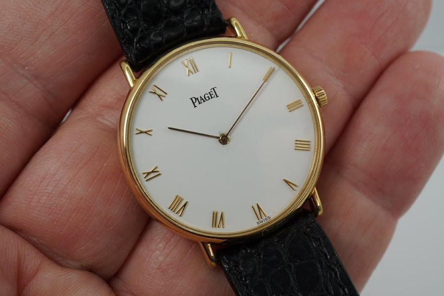 A very nice preowned Piaget watch in 18k yellow gold reference 8035, crafted during the 1990-2000s. A classic configuration of understated gold round smooth case, white dial and gold applied hours and Roman numerals. This piece will take you from executive look to a casual occasion, featuring an ultra-thin profile and paired with a black strap. Suitable for men or women.

Minimal scratches. 
Original dial, hands and crown.
Case measures 32.5 x 35 mm, 4.5mm thick. 
Piaget cal. 858P quartz movement. 
Case# 594500 Movement# 9901021 
Sapphire crystal. 
Piaget black crocodile strap (80% condition approximate).
Piaget 18k gold buckle.
17mm lug width.