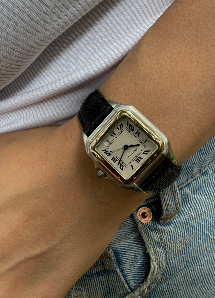 A fine Cartier Panthere reference 1100 in 18k yellow gold and stainless steel, crafted circa 1995. An everyday accessory that would suit a variety of occasions with its non-overpowering square satin finish steel case offset with polished gold bezel. Featuring the signature silvered grain dial with black Roman numerals, blued sword-shaped hands and date aperture located 5 o’clock position, and octagonal blue sapphire cabochon. The 6mm profile and deployment buckle allows this piece to wear comfortably on the wrist.  

Light scratches. 
Original box and papers.
Original dial, hands and crown. 
Case measures 27 x 36mm, 6mm thick.
Cartier quartz movement. 
Serial# C922xx
Sapphire crystal.
New non-Cartier black lizard adjustable strap.
Cartier steel deployment buckle.
15mm lug width.
Modeled on 6 inch wrist.