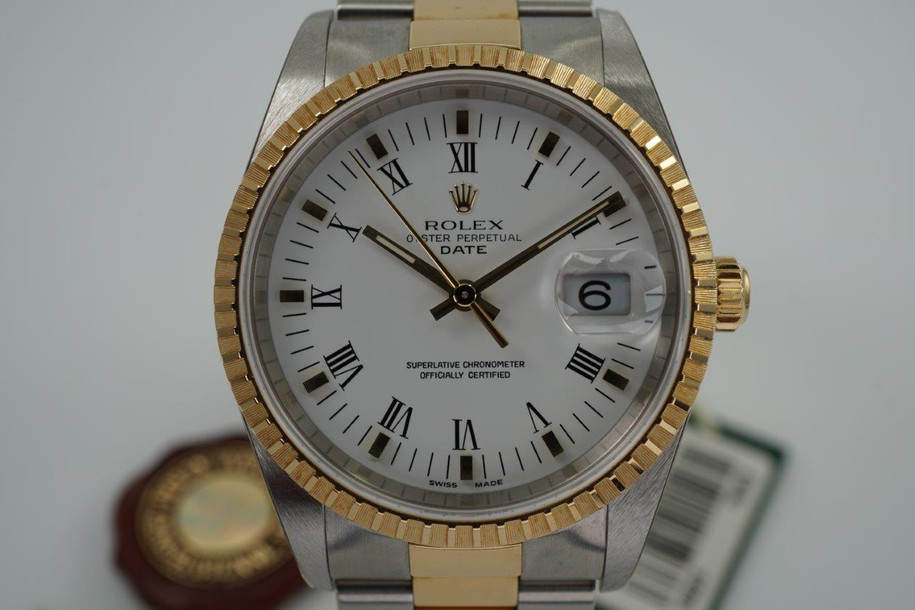 A fine new old stock Rolex Date reference 15223 in 18k yellow gold and stainless steel, crafted circa 2005. In unpolished condition, as if it left the Rolex boutique with tags attached and very little wear, if any, shown and still adhered original Rolex stickers. Featuring a 34.5 mm two-tone case housing a white dial with gold applied hour markers and hands, black numeral hours and minute markers, with date aperture, engine turned gold bezel and a two-tone oyster bracelet with adjustable fold clasp. A popular and enduring model to wear for various occasions.