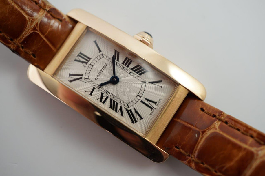 A fine preowned Cartier Tank Americaine with Cartier card, crafted circa 2018. This Tank model from Cartier may not be as popular as its other variants, we think this particular configuration of the petite albeit beefy rectangular 19 mm rose gold polished and brushed finish case paired with the saddle colored crocodile strap create a fetching accessory, notably so with the guilloche dial backdrop to the standard black Roman numeral hours with an inconspicuous Cartier signature at 7 o’clock, inner chemin de fer minute track and blued-steel sword-shaped hands, topped with a faceted gold and blue sapphire crown. The slightly elevated 6.5 profile adds more impact to the wrist, for that carefree wear that is suitable for a variety of occasions.