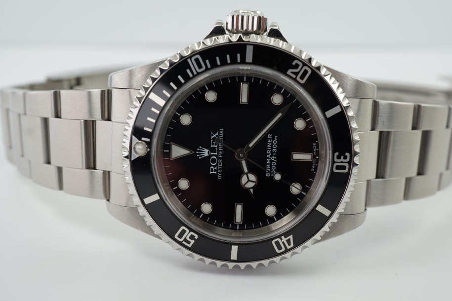 A fine preowned Rolex Submariner non-date reference 14060M in stainless steel originally sold in Hong Kong with papers dated Jan. 2003 and tags, crafted circa 2003. Classic and enduring 40 mm case for casual wear with black bezel, black dial and large lume white round and baton hour markers, and white lume sword-shaped hands. 13 mm silhouette with flip lock steel clasp for secured and comfort fit.

Light wear, small nick located bottom right lug.
Original dial, hands, and crown.
Case measures 40 x 47 mm, 13 mm thick.  
Rolex cal. 3130, highly jeweled automatic winding.
Sapphire crystal.
Serial# Y2135xxx
Rolex flip lock steel bracelet fits 7 3/4 inches.
20 mm between lugs.
Modeled on size 7 3/4 inch wrist.