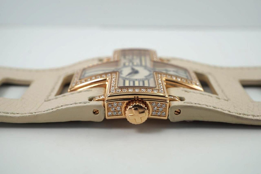 A fine preowned Roger Dubuis Follow Me reference F1685 in 18k rose gold, crafted circa 2000. Factory set in approximately 248 diamonds, on side of the case, bezel, lugs and cross buckle. Carat weight approximately 5 carats. Beautiful guilloche dial with large outlined Roman hour markers located at each cross ends, blued-steel sword-shaped hands housed in a 39mm case shaped as a cross. The linen color wide leather strap is similar to the H bracelet from Hermes, making a bold statement on the wrist that is securely fastened with two buckles.

Minimal scratches/nick.
Original guilloche dial, hands and crown. 
Case measures 39 x 39mm, 8mm thick.
Quartz movement.
Sapphire crystal.
Roger Dubuis leather strap, 39mm band width. 
Roger Dubuis 18k rose gold buckles.