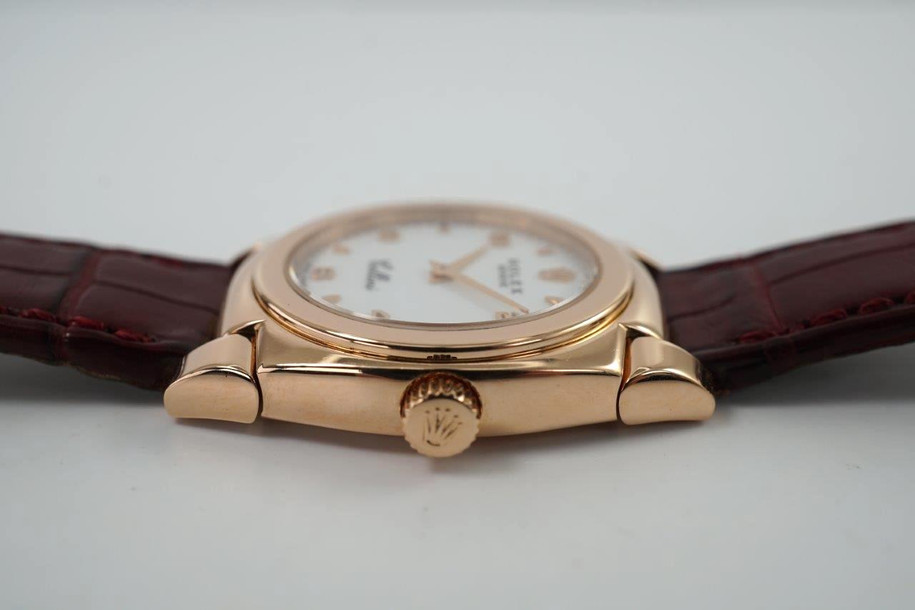 A fine vintage Rolex Cellini Cestello reference 5310 in 18k rose gold, crafted circa 1999. Dainty from its polished cushion-shaped 26mm case and slim 6mm silhouette with flexible lugs, smooth bezel housing a white dial, small rose gold Arabic/ tear drop hour markers, and sword-shaped hands. Paired with burgundy crocodile strap complimenting the rose gold. 

Minimal scratches.
Original dial, hands and crown. 
Case measures 26 x 32mm, 6mm thick.
Rolex cal. 1602, 20 jewels mechanical winding.
Sapphire crystal.
Serial# A8412xx
Rolex burgundy crocodile strap (80% condition approximation).
Rolex 18k rose gold buckle.
Modeled on a 6 inch wrist.