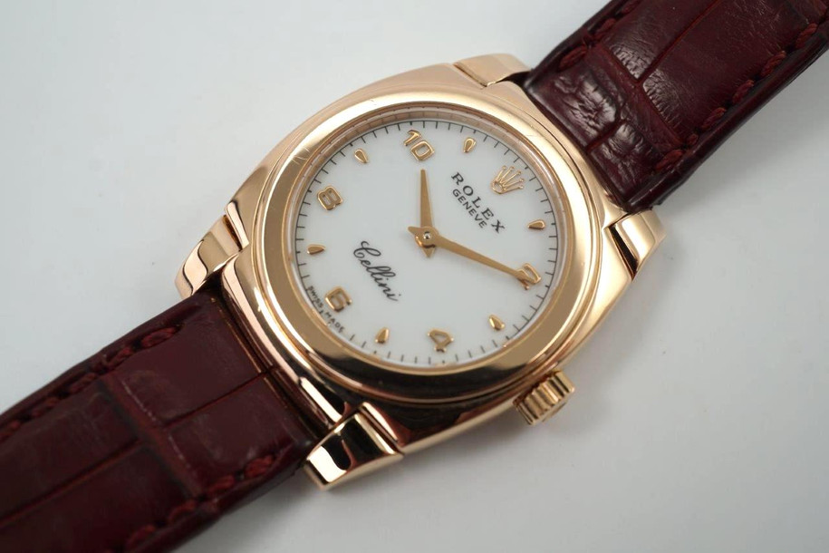 A fine vintage Rolex Cellini Cestello reference 5310 in 18k rose gold, crafted circa 1999. Dainty from its polished cushion-shaped 26mm case and slim 6mm silhouette with flexible lugs, smooth bezel housing a white dial, small rose gold Arabic/ tear drop hour markers, and sword-shaped hands. Paired with burgundy crocodile strap complimenting the rose gold. 

Minimal scratches.
Original dial, hands and crown. 
Case measures 26 x 32mm, 6mm thick.
Rolex cal. 1602, 20 jewels mechanical winding.
Sapphire crystal.
Serial# A8412xx
Rolex burgundy crocodile strap (80% condition approximation).
Rolex 18k rose gold buckle.
Modeled on a 6 inch wrist.