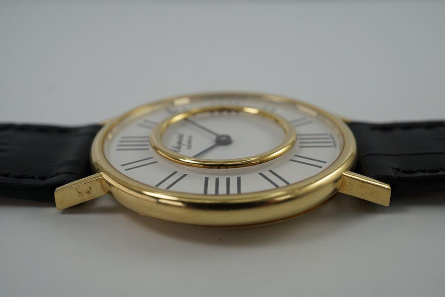 A very cool preowned Chopard watch in 18k yellow gold, crafted during the 1970s. A design that we have yet to come across, with an inner gold bezel surrounded by black hour markers we cannot distinguish what they represent. The 12, 3, 6, and 9 o'clock contain four hash marks while the rest contain two. Classic white dial and black hour markers and hands, yet distinctive from the standard in a 34mm round case and slim 6 mm silhouette would suit a variety of wrists and wardrobes. 

Original dial, hands and L.U.C. crown. 
Case measures 34 x 38 mm, 6mm thick.
Chopard L.U.C. cal. P7001, 17 jewels manual wind.
Sapphire crystal.
Serial# 146442-1048
New non-Chopard black leather strap.
17mm lug width.