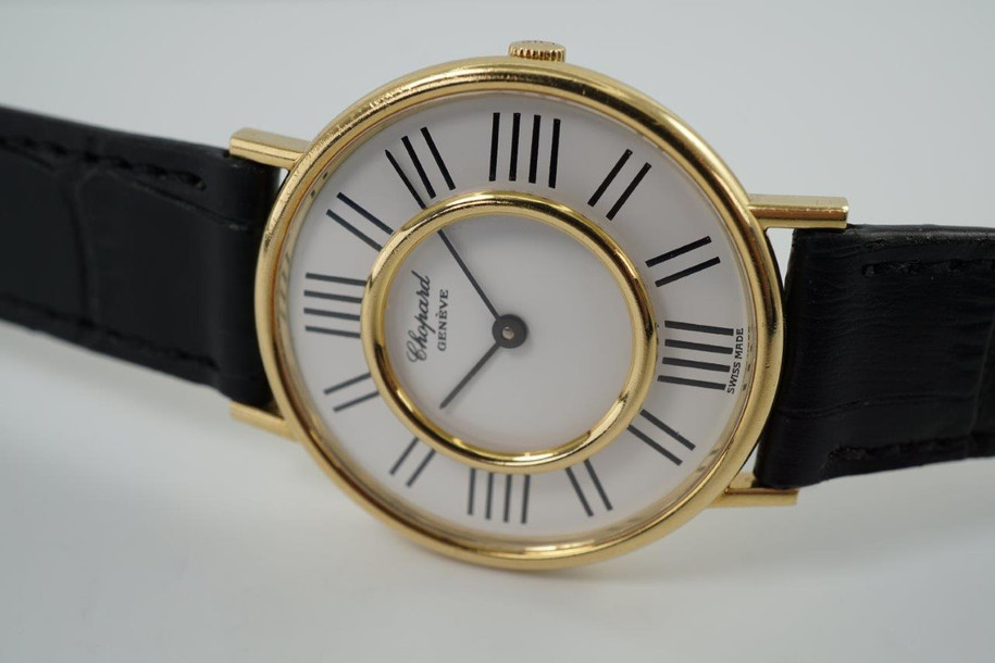 A very cool preowned Chopard watch in 18k yellow gold, crafted during the 1970s. A design that we have yet to come across, with an inner gold bezel surrounded by black hour markers we cannot distinguish what they represent. The 12, 3, 6, and 9 o'clock contain four hash marks while the rest contain two. Classic white dial and black hour markers and hands, yet distinctive from the standard in a 34mm round case and slim 6 mm silhouette would suit a variety of wrists and wardrobes. 

Original dial, hands and L.U.C. crown. 
Case measures 34 x 38 mm, 6mm thick.
Chopard L.U.C. cal. P7001, 17 jewels manual wind.
Sapphire crystal.
Serial# 146442-1048
New non-Chopard black leather strap.
17mm lug width.