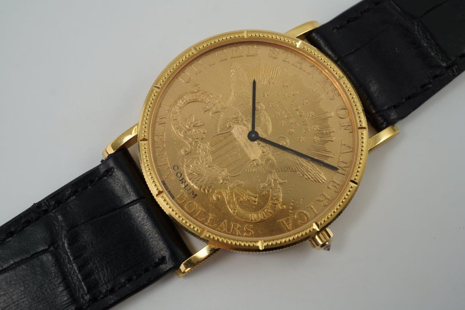 A near mint Corum $20 1900 Liberty US coin watch in 18k yellow gold, crafted during the 1990s. Features classic ridge-edged, beaded minute and notched hour markers on bezel, black-steeled sword-shaped hands and diamond crown. Durable for everyday wear, making a lovely golden statement on the wrist. 

Original dial, hands and diamond crown.
Case measures 35 x 42mm, 4.5mm thick.
High grade Swiss mechanical movement, 18 jewels, 3 adjustments.
Case# 5762xx Movement# 5225xx
Sapphire crystal.
New non-Corum black leather strap.
Fits up to 7 1/5 inches.
Corum 18k tang buckle.
20mm lug width.
Modeled on 6 inch wrist.