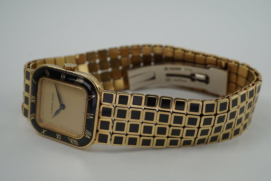 A wonderfully rare Audemars Piguet ladies bracelet watch in 18k yellow gold and black enamel, crafted during the 1980s. A rare and beautiful piece featuring a stylized tile design in the supple bracelet. Gold dial with black leaf hands and minute track, surrounded by black enamel bezel with gold Roman numeral hour markers. The 4-tile motif bracelet is perfectly proportioned for its 22.5mm square case with a deployant clasp providing a seamless look. This slim 5mm silhouette piece wears comfortably and is unseen on the market, making it a beautiful addition for a vintage lover’s collection. 

Enamel bezel contains a crack between 9 and 10 o’clock.
Original dial, hands and crown.
Case measures 22.5 x 24mm, 5mm thick.
Audemars Piguet cal. 2080, 20 jewels mechanical winding.
Case# C177xx Movement# 2822xx
Sapphire crystal.
Audemars Piguet 18k and enamel bracelet, fits 6 1/2 inches or 16.5 cm. 
16mm bracelet width.
Modeled on 6 inch wrist.