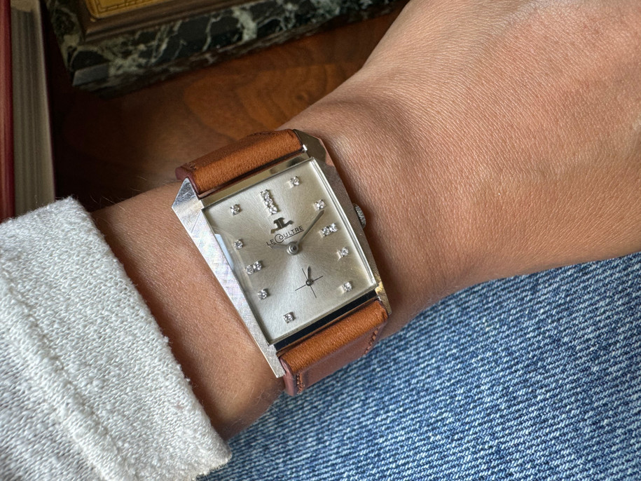 A vintage LeCoultre Asymmetrical reference 2406 in 14k white gold, crafted circa 1950. The curiously shaped case measures 28 mm across and tapers to 23 mm with a 9 mm thickness due the domed glass crystal. The bezel contains finely hatched texture and houses a silvered dial with diamond hour markers, silver sword-shaped hands, subsidiary dial and a short crown stamped JL. Rare to find this timepiece in unpolished and beautiful condition, would made an excellent addition to a vintage lover’s collection.