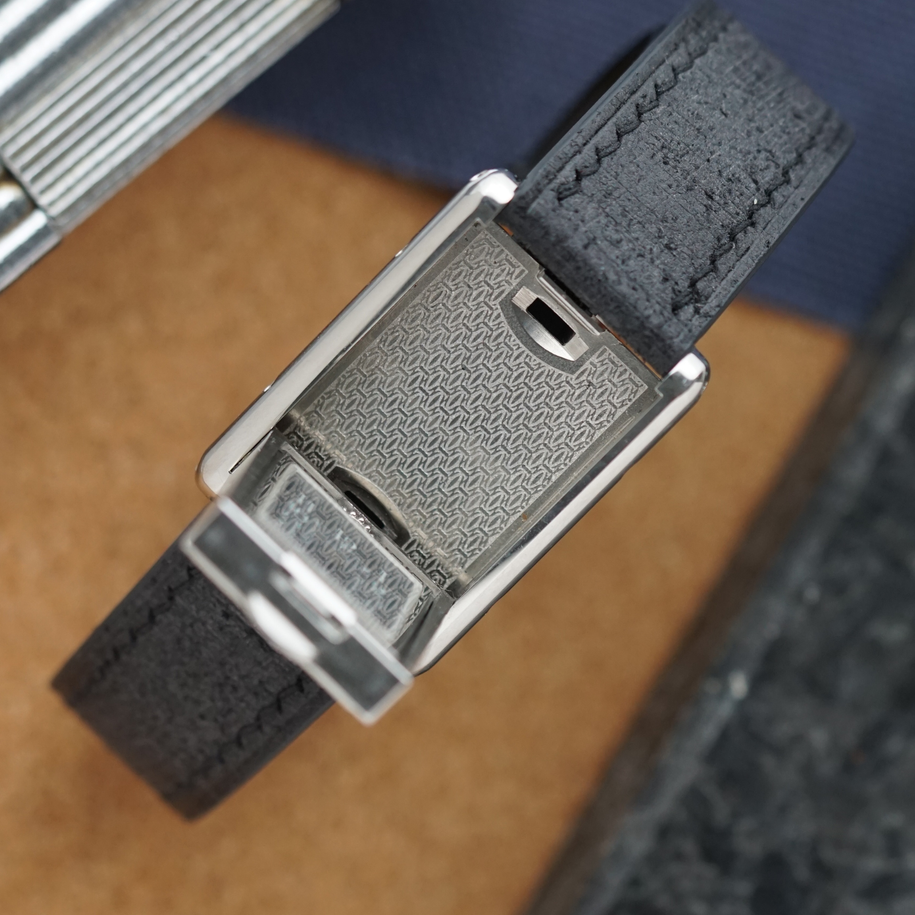 A late 1990s Cartier Tank Basculante in stainless steel, wonderfully constructed in a compact 22mm size. The dark grey patterned dial is contrasted by bright white stylized Arabic numerals and silvered sword-shaped hands, giving the watch a distinctive monochromatic look.
The Basculante's hinged case is the highlight of the design, allowing the watch head to pivot within its frame and turn completely over. It opens and closes smoothly and can remain upright within the frame. A blue cabochon accents the case, while the crown is cleverly concealed and accessed only when the watch is flipped from its usual position.
Powered by a quartz movement and fitted with a custom dark grey Babele leather strap secured by a Cartier stainless steel deployant clasp. An unusual interpretation of the Tank, with much of its appeal found in the ingenious case construction.

Watch Details
Reference: 2386
Case Number: 3514xxxx
Case: Stainless steel
Case Size: 22 × 32 mm; 6 mm thick
Dial: Dark grey patterned dial; white Arabic numerals
Movement: Quartz
Crystal: Sapphire
Strap: Custom dark grey Babele leather, adjustable
Lug Width: 17 mm
Clasp: Cartier stainless steel deployant
Wrist Size: Fits up to approximately 6 1/2 inches
Modelled On: 6-inch wrist
Condition: Light wear shown
Service: New battery installed