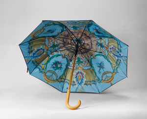 Open umbrella resting on a white surface with a multicolor print on the inside. Open umbrella resting on a white surface with a multicolor print on the inside.