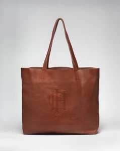 Leather brown tote with the words The Frick Collection and its logo on its side and straps standing upright forming a triangle