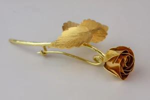 Gold rose pin laid flat.