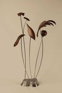 An abstract sculptural arrangement of 5 slender metal stems with wooden motifs (made of walnut) representing a frond, leaf, flower, peapod, and a nutmeg or pomegranate.