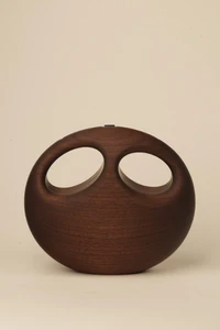 Dark walnut wood handbag with two oval openings forming an owl-like face, photographed closed against a neutral background.