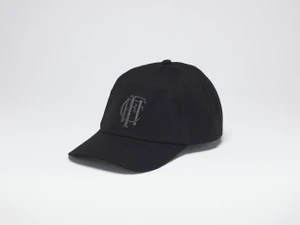 Black baseball hat with the charcoal embroidered Frick Collection logo on the front, sitting on a white surface.