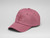 Pink baseball cap sitting on a white surface