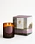 Glass candle featuring two lit wicks and the Frick monogram stamped on the container. A boxed package is featured next to it.